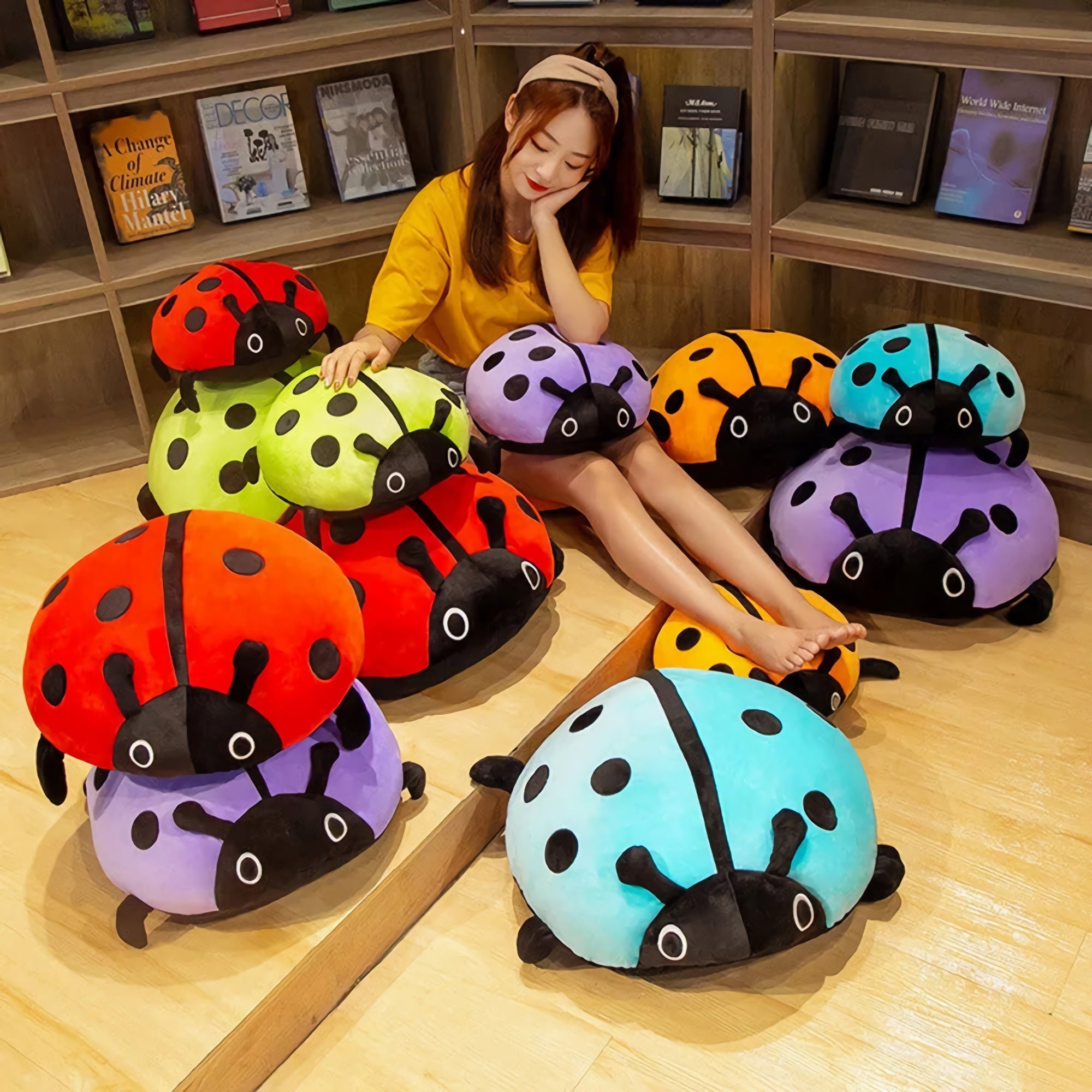 A person sits among colorful squishy ladybug plush pillows in a cozy indoor setting.
