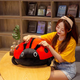 A person sits at a table, interacting with a large, colorful ladybug plush pillow.