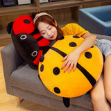 A person rests on colorful ladybug-shaped plush pillows while sitting on a couch.