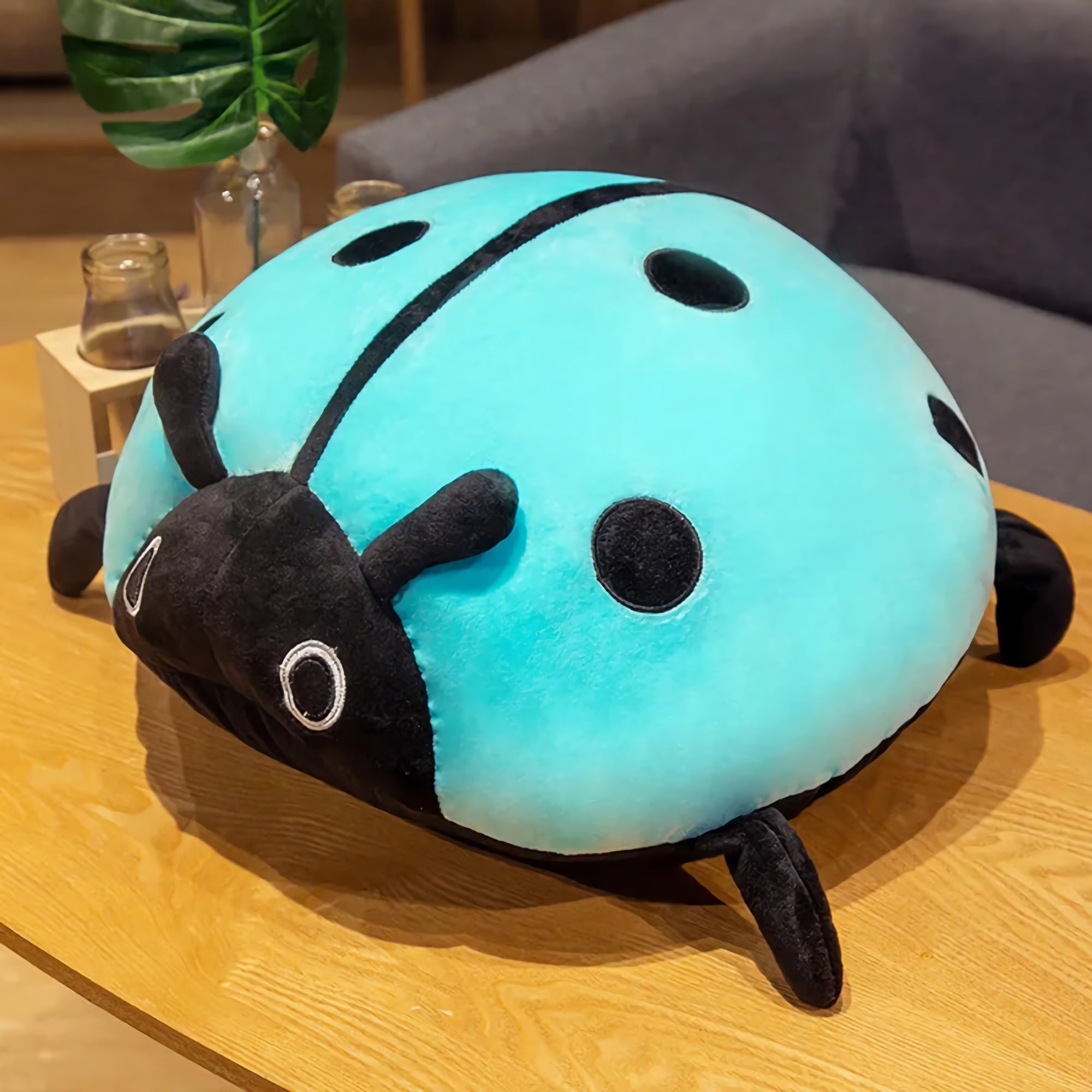 A blue and black ladybug-shaped plush pillow on a wooden table.