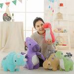 A person holding a red and white dinosaur plush toy surrounded by four other pastel dinosaur plush toys.