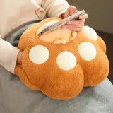 A child holds a plush, paw-shaped hand warmer while using a smartphone, with a soft blanket draped over their lap.