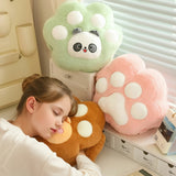 Girl sleeping on a plush paw-shaped pillow with two other plush pillows nearby.