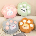 Four plush paw-shaped cushions in pastel colors, featuring cute animal faces: bunny, panda, cat, and bear.