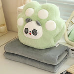 Green plush paw-shaped pillow with a panda face on top of a folded gray blanket.