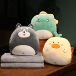 Three plush animal pillows in gray, green, and yellow, with two gray travel blankets stacked underneath.