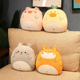 Four plush pillows shaped like animals, including a pig, duck, cat, and dog, arranged on a couch.