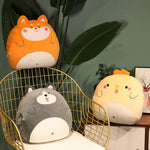 Three plush animal pillows on a chair and table, with a plant in the background.