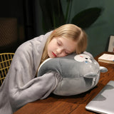 Child sleeping on a plush animal pillow with a blanket at a table.