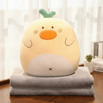 Plush toy with a round face and green tuft on top, sitting on a folded gray blanket.