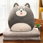 Gray plush animal pillow with a smiling face on top of a folded gray blanket.