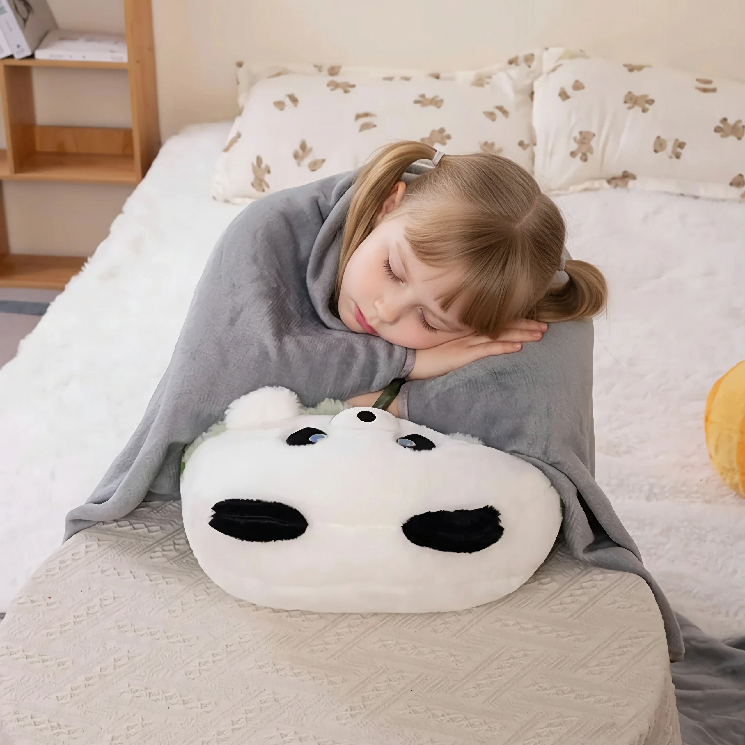 Child sleeping on a panda-shaped pillow with a gray blanket.