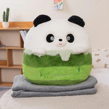 Plush panda-shaped pillow with green and white colors, resting on two gray travel blankets.
