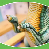 Close-up of a plush dinosaur toy's textured claws and striped body against a blurred background.
