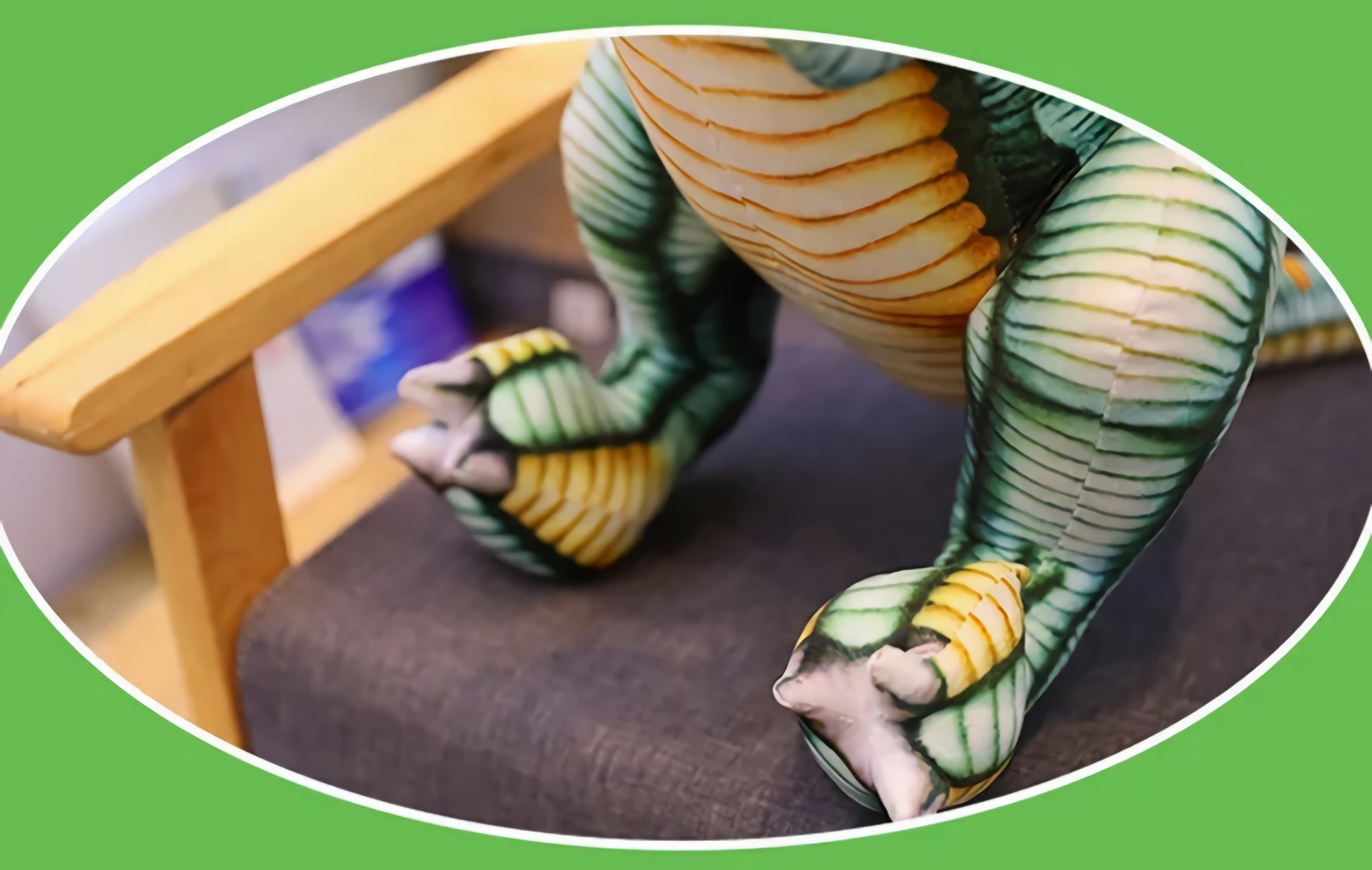 Close-up of a Spinosaurus plush toy's feet and legs, featuring green and yellow detailing, resting on a chair.
