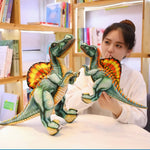 A person holds two colorful Spinosaurus plush toys while sitting at a table in a library setting.
