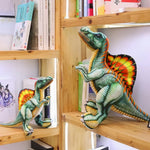 Two Spinosaurus plush toys with colorful details displayed on wooden shelves among books.