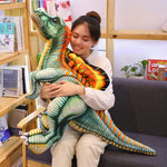A person hugs a large, colorful Spinosaurus plush pillow while sitting on a couch in a cozy room.