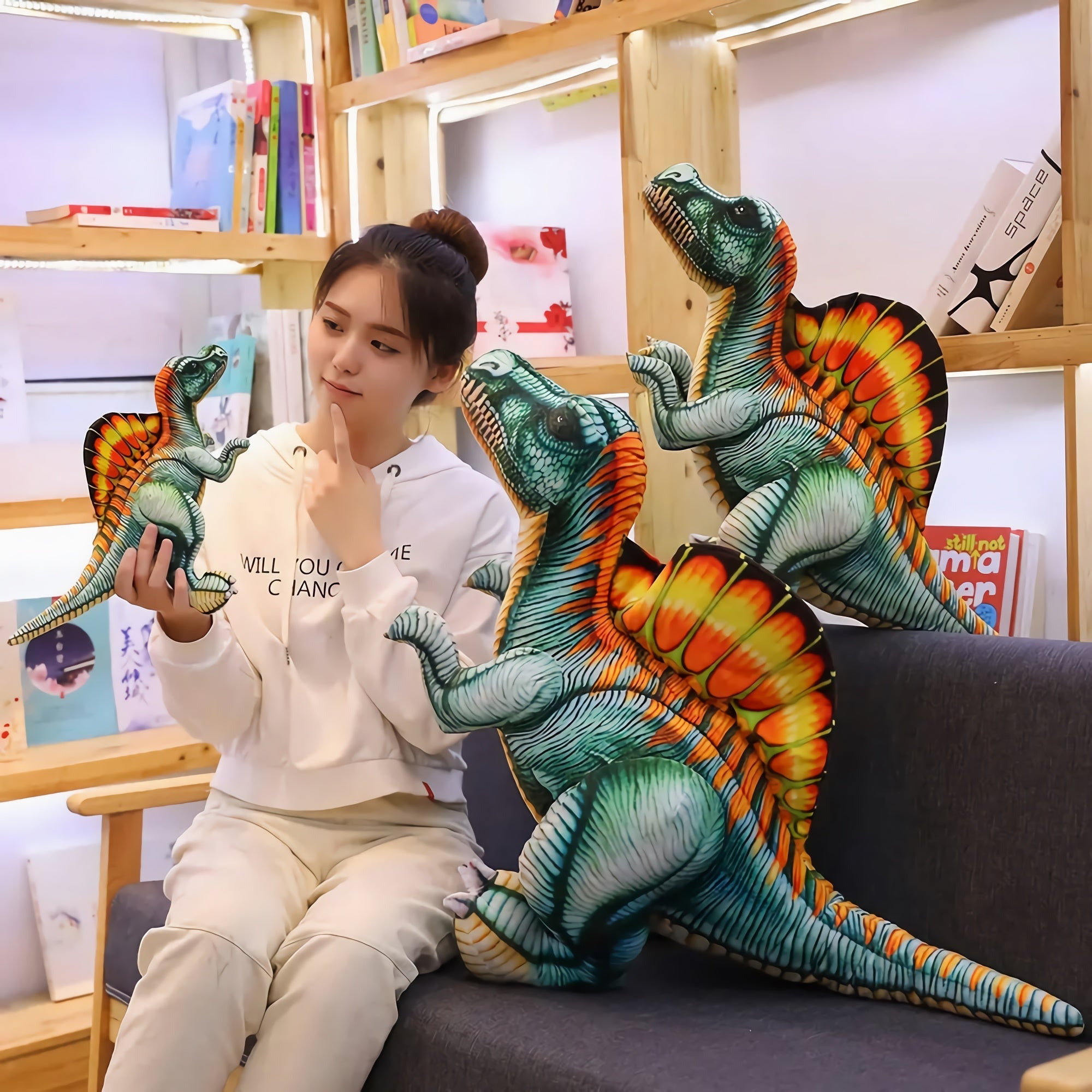 A person sits on a couch with colorful Spinosaurus plush toys, contemplating while holding one in their hand.