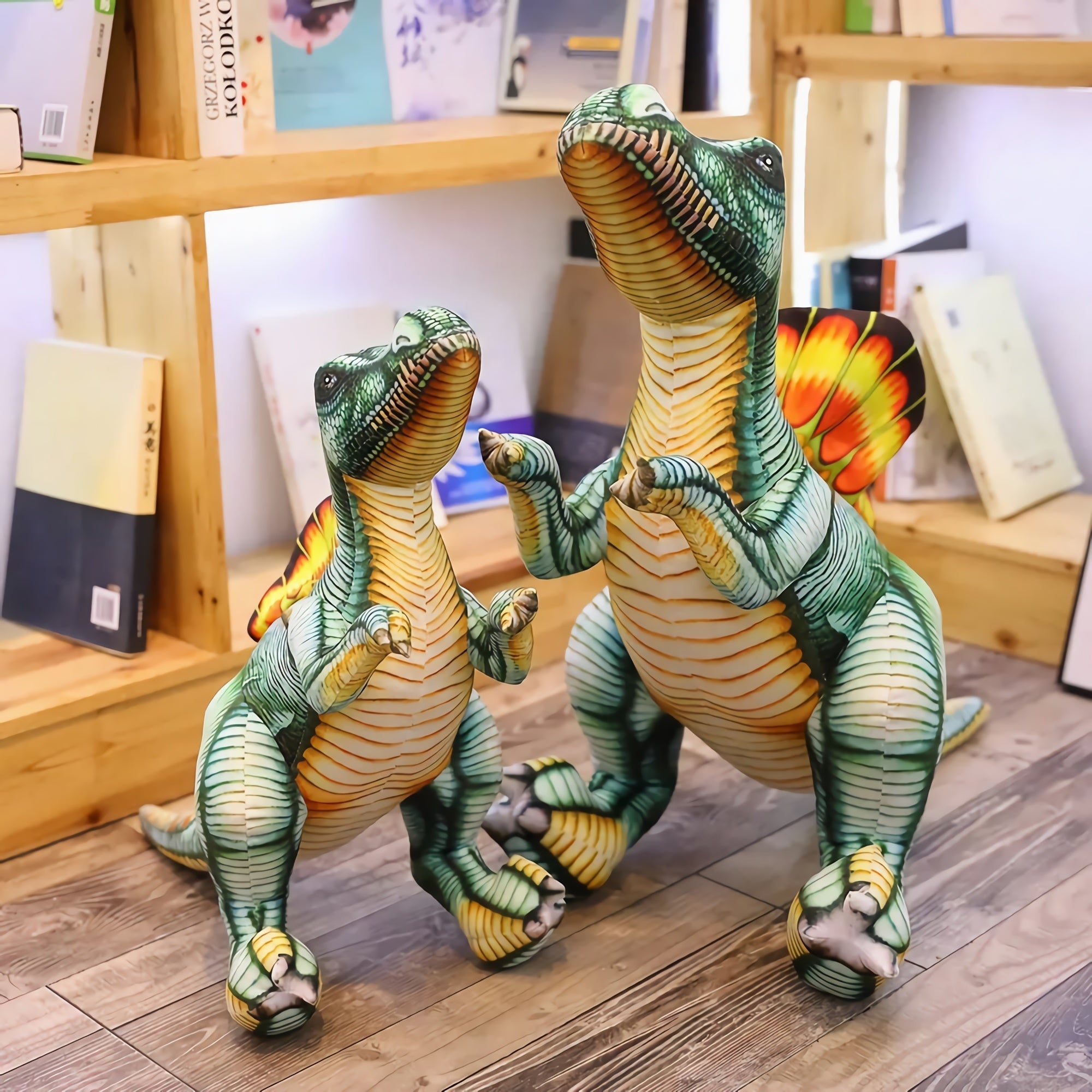 Two plush Spinosaurus dinosaur toys standing on a wooden floor with bookshelves in the background.